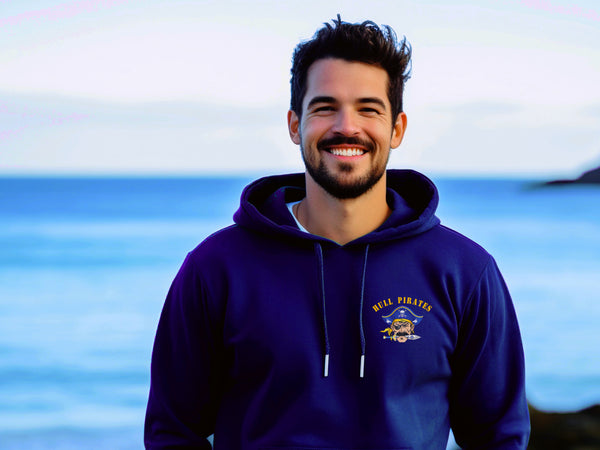 Man wearing a royal blue hoodie with a logo standing by the ocean