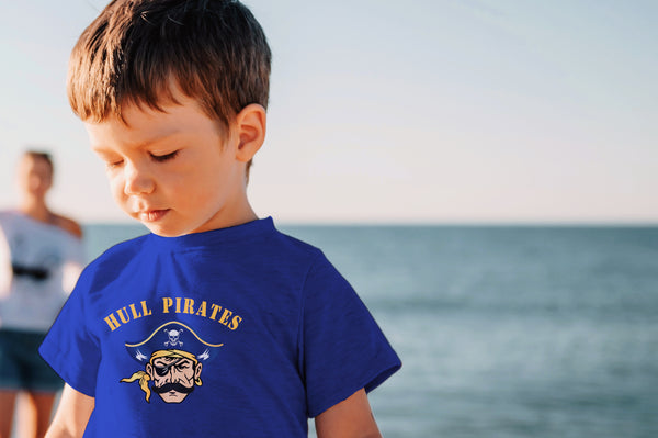 Child wearing a blue 'Bull Pirates' t-shirt by the ocean