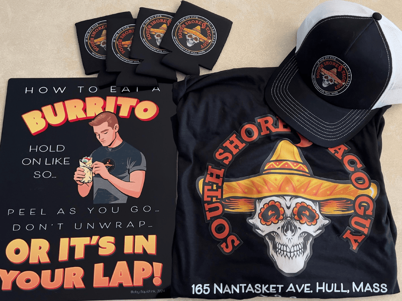 T-shirt with burrito graphic and text, cap, and coasters on a beige surface