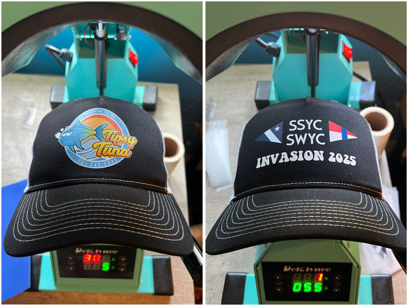Two black hats with different designs on a press machine.