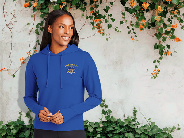 Woman wearing a blue hoodie with a logo against a wall with greenery