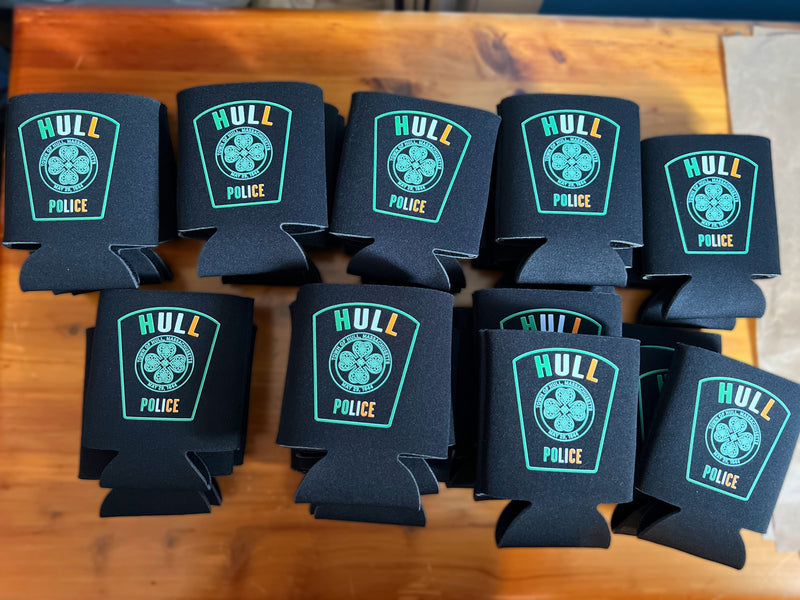 Black can coolers with 'Hull Police' logo arranged on a wooden surface