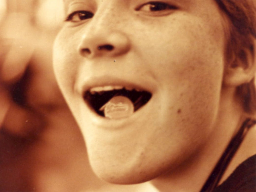 Close-up of a person with their tongue out, in sepia tone.
