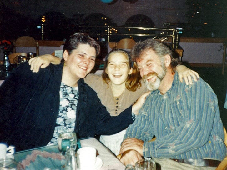 Three people posing together outdoors at night.