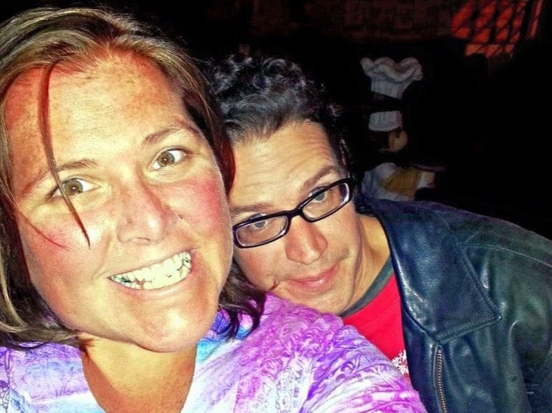 Two people posing for a selfie with a dark background