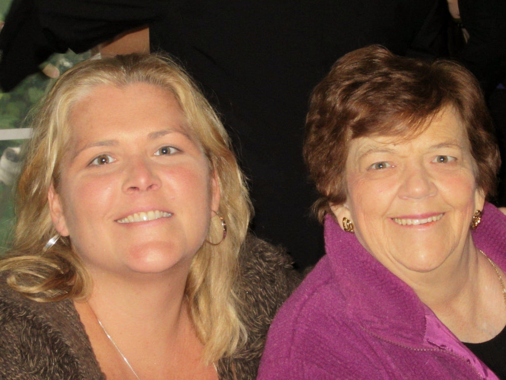 Two women standing close together, one with blonde hair and the other with brown hair, both wearing jackets.