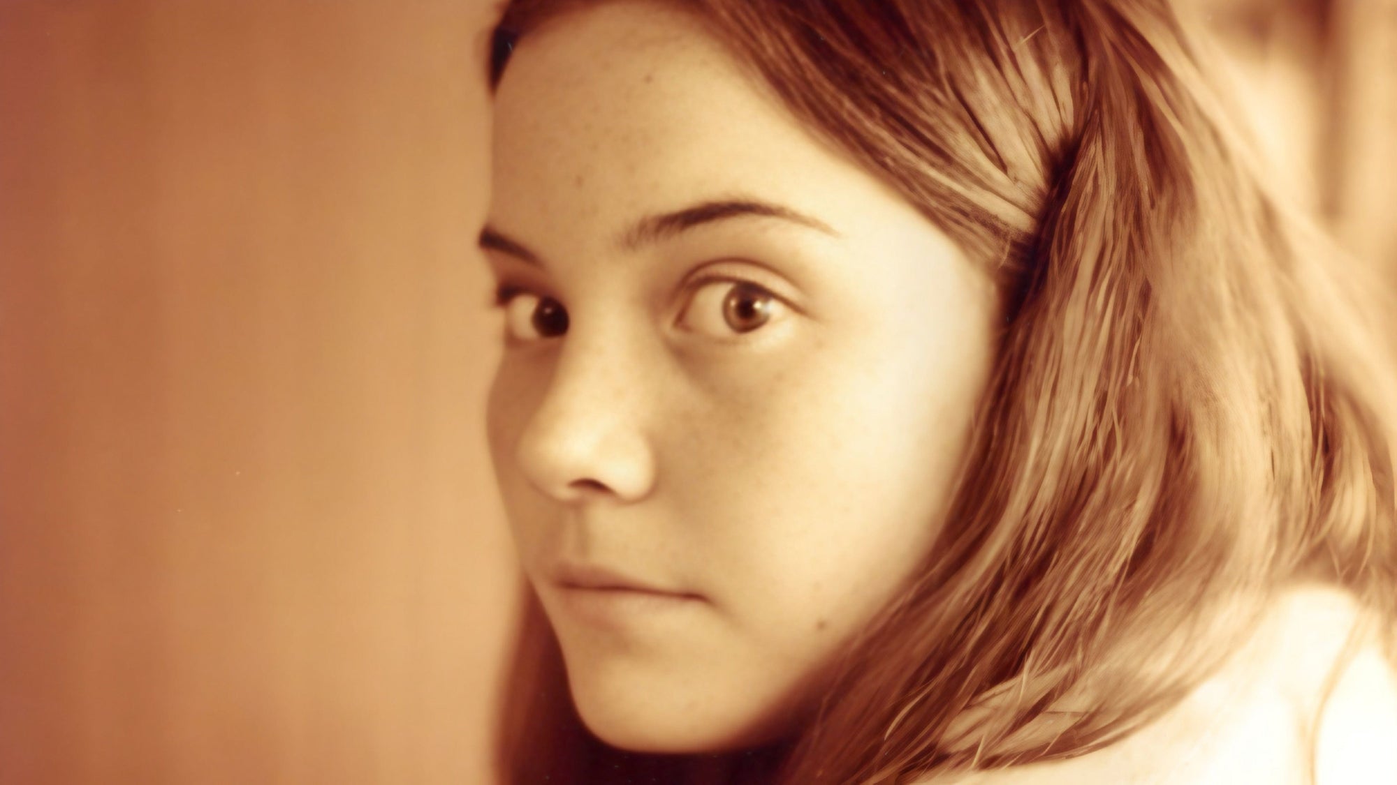 Close-up of a person with a neutral expression against a plain background