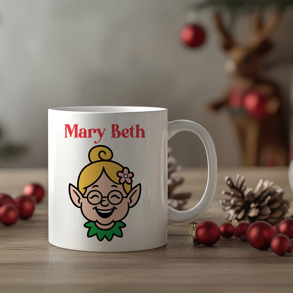 White mug with an elf design and 'Mary Beth' text, surrounded by Christmas decorations.