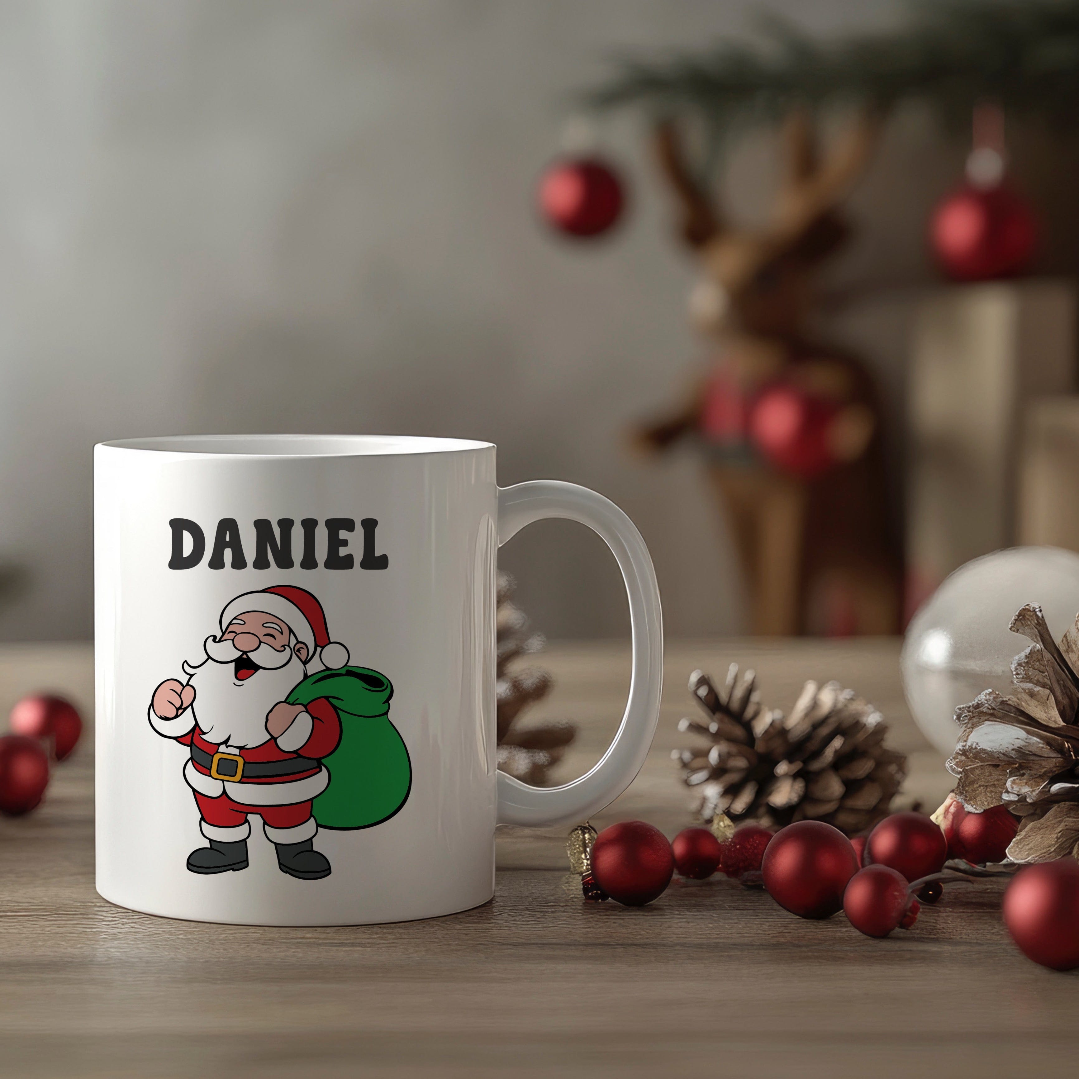 White mug with a cartoon Santa Claus design and 'DANIEL' text, placed on a wooden surface with Christmas decorations.