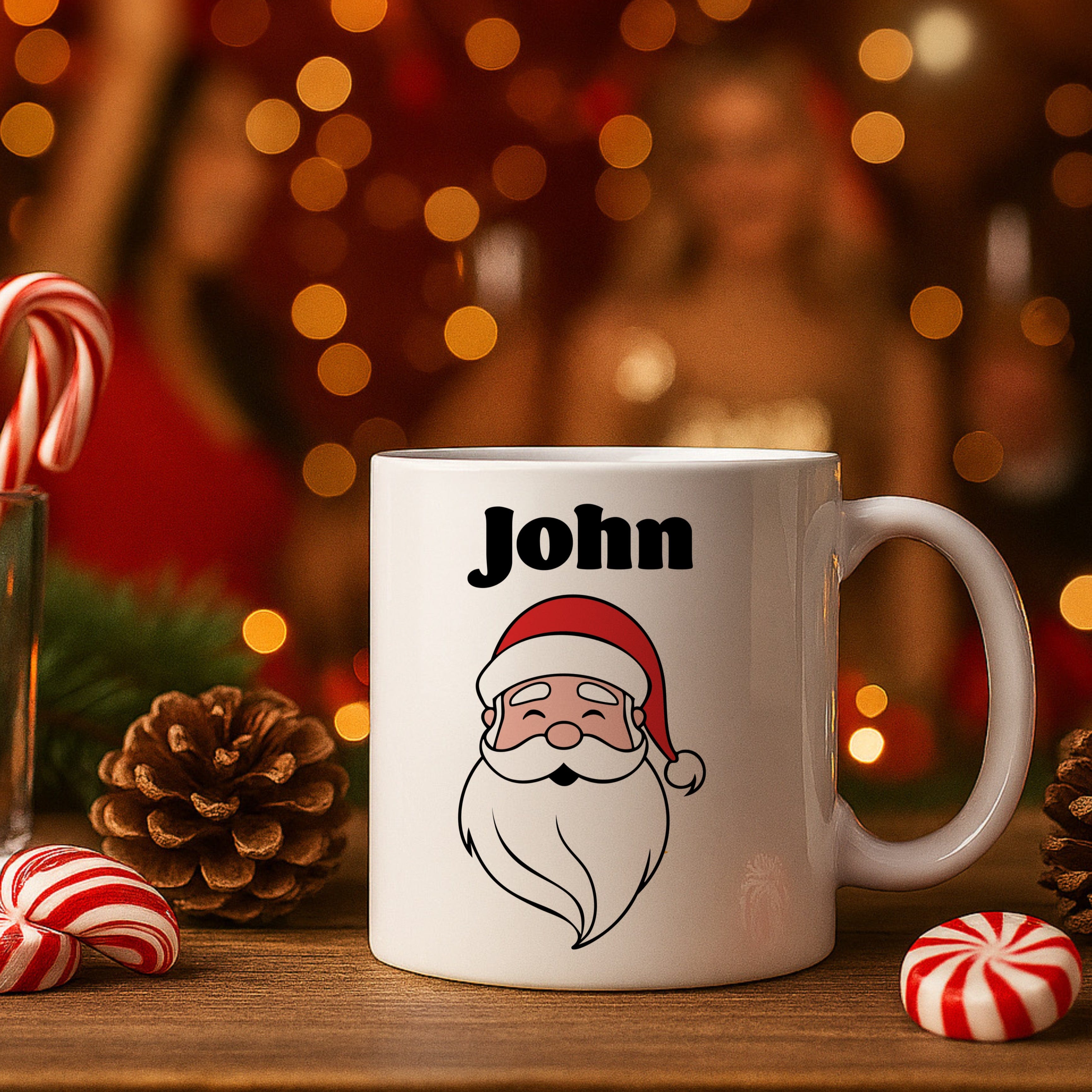 White mug with Santa Claus design and 'John' text, surrounded by Christmas decor on a wooden surface.