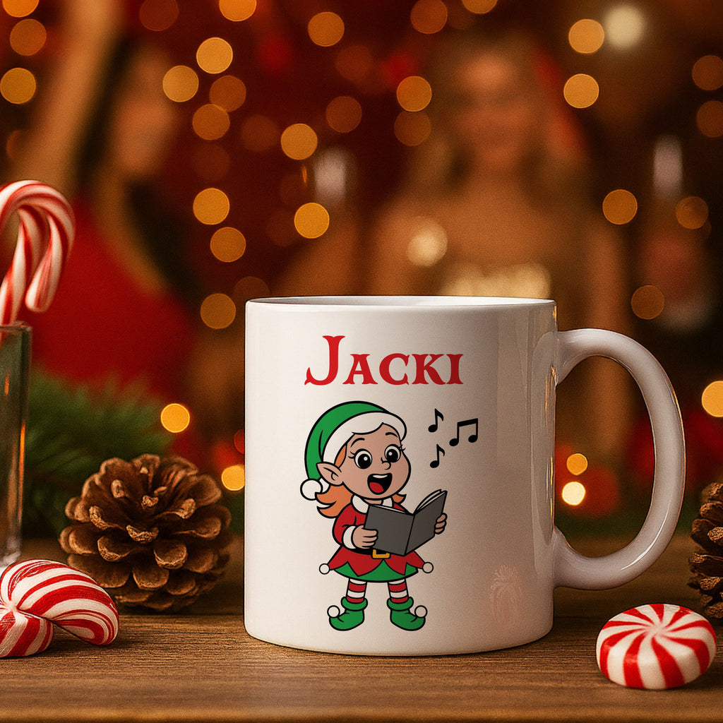 White mug with 'Jacki' and an elf design on a wooden surface with Christmas decorations.