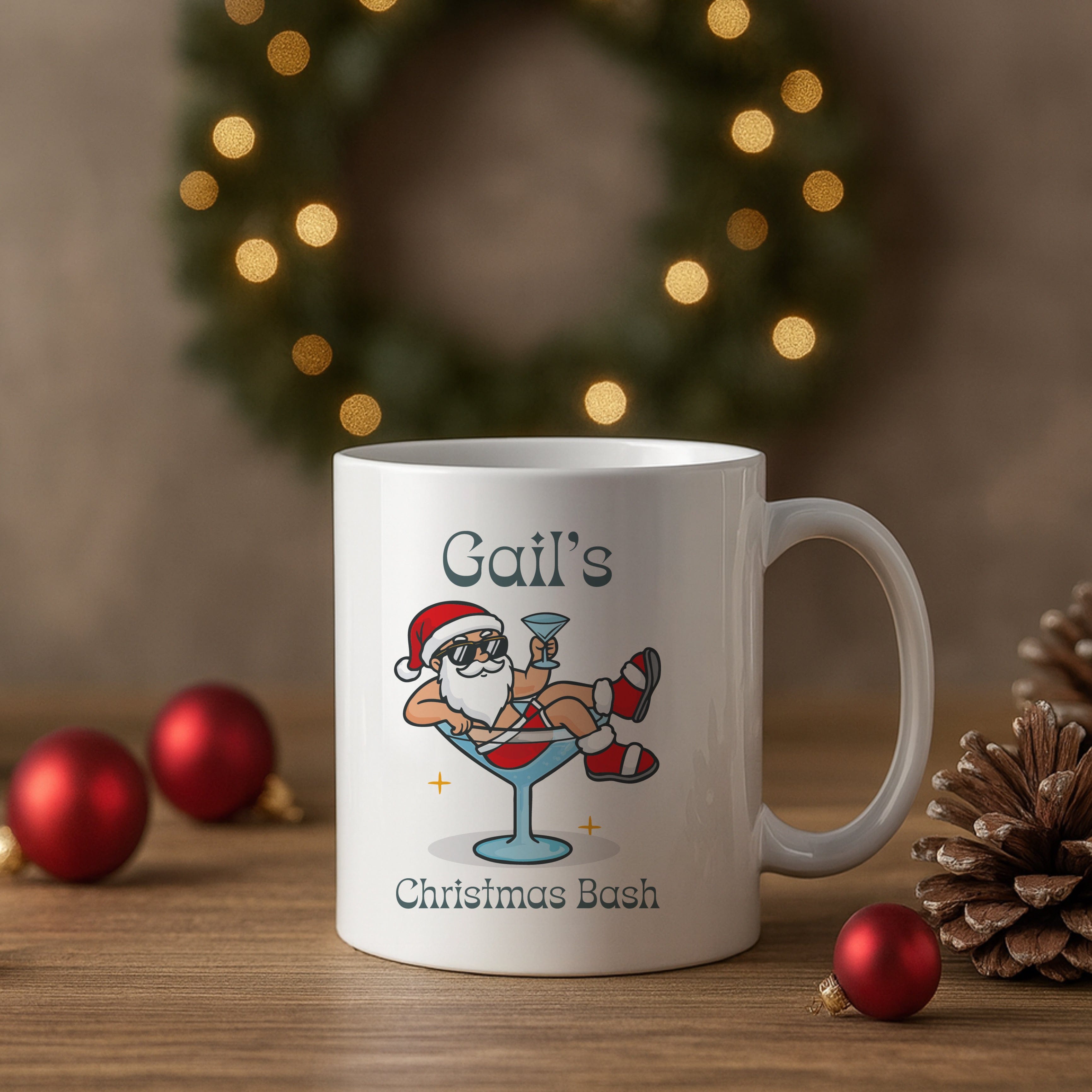 White mug with a festive design of a cartoon Santa Claus on a martini glass, placed on a wooden surface with Christmas decorations.