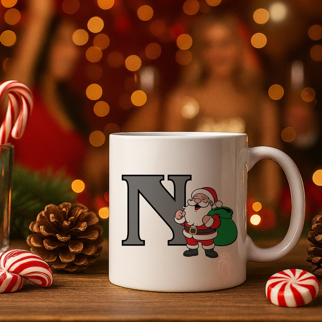 White mug with Santa Claus design and letter 'N' on a festive background with candy canes and pine cones.