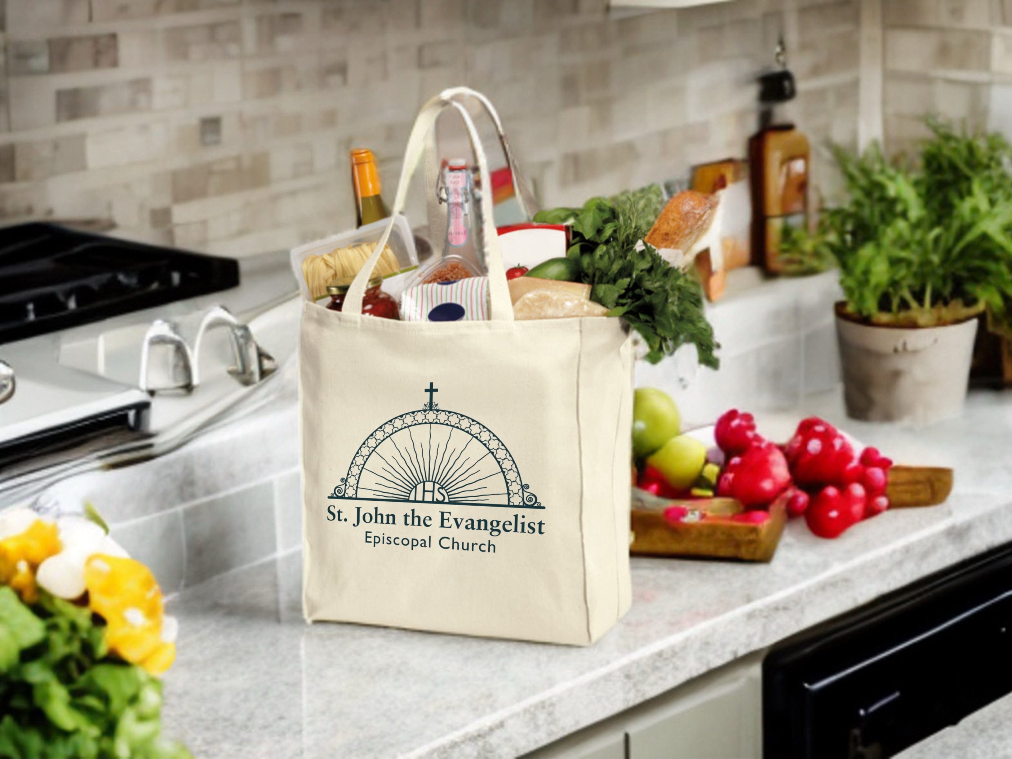 Tote bag with 'St. John the Evangelist Episcopal Church' logo on a kitchen counter with groceries.